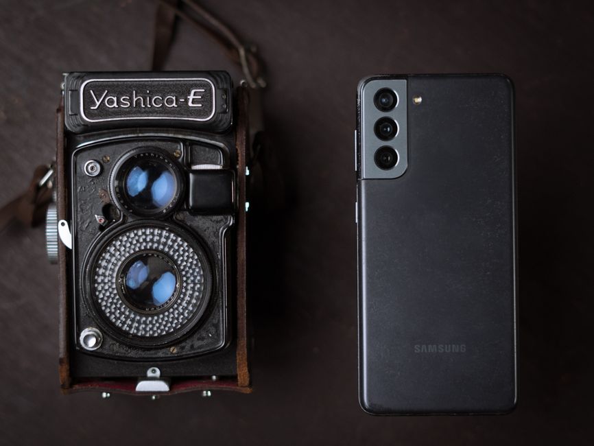 現代のスマートフォンの隣にある古いカメラ