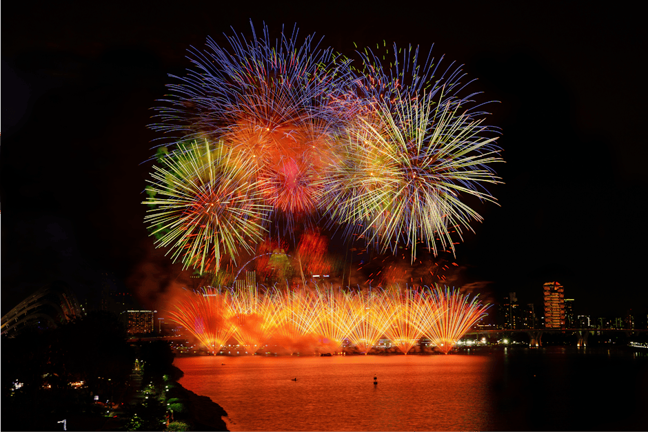 鮮やかな花火が街並みと水辺の夜空を照らし、魅惑的な光景を作り出します。