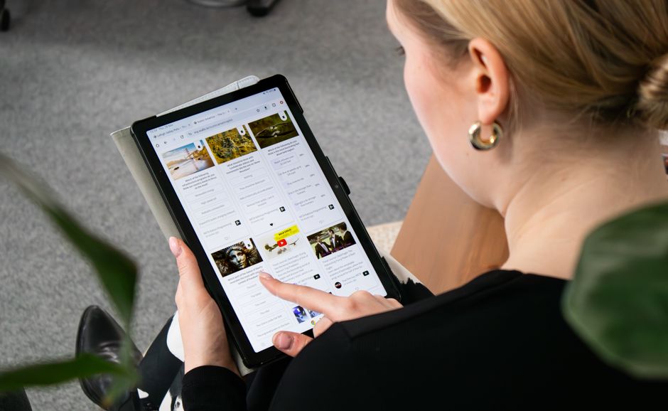 オフィス環境に座ってタブレットでウェブを閲覧する女性