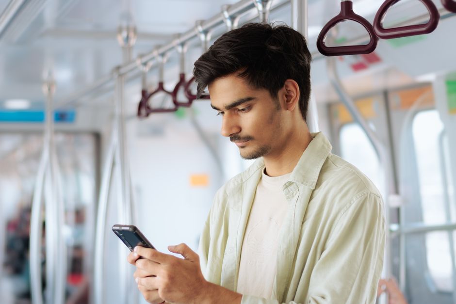 公共交通機関でスマートフォンを使用する若い男性