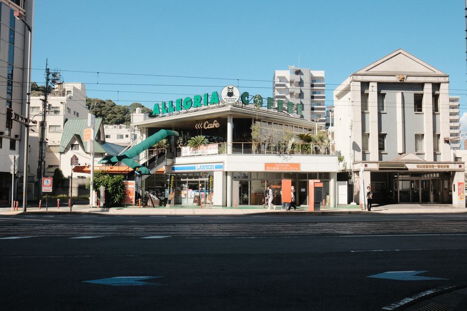 晴れた日のコーヒーショップと周囲の建物を描いた明るい都市の風景。
