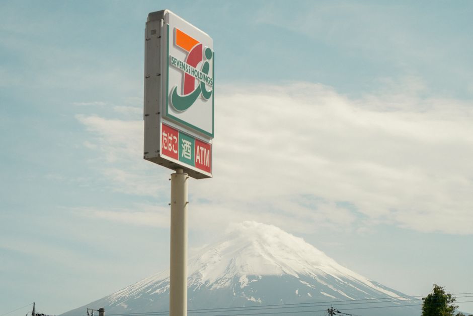 澄み切った空の下、背景に富士山が見えるコンビニエンスストアの看板。