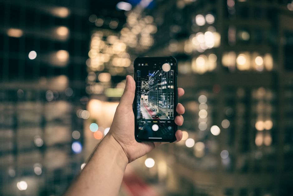 スマートフォンで夜の街並みを撮影する手元（夜景撮影の比較イメージ）
