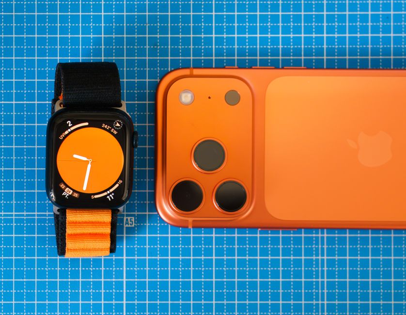 青い格子模様の背景に、オレンジを基調としたスマートフォンとスマートウォッチを配置した、ミニマルなレイアウト。